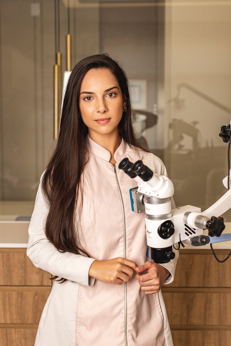 Dra. Izabela Dutra ao lado do microscópio operatório
